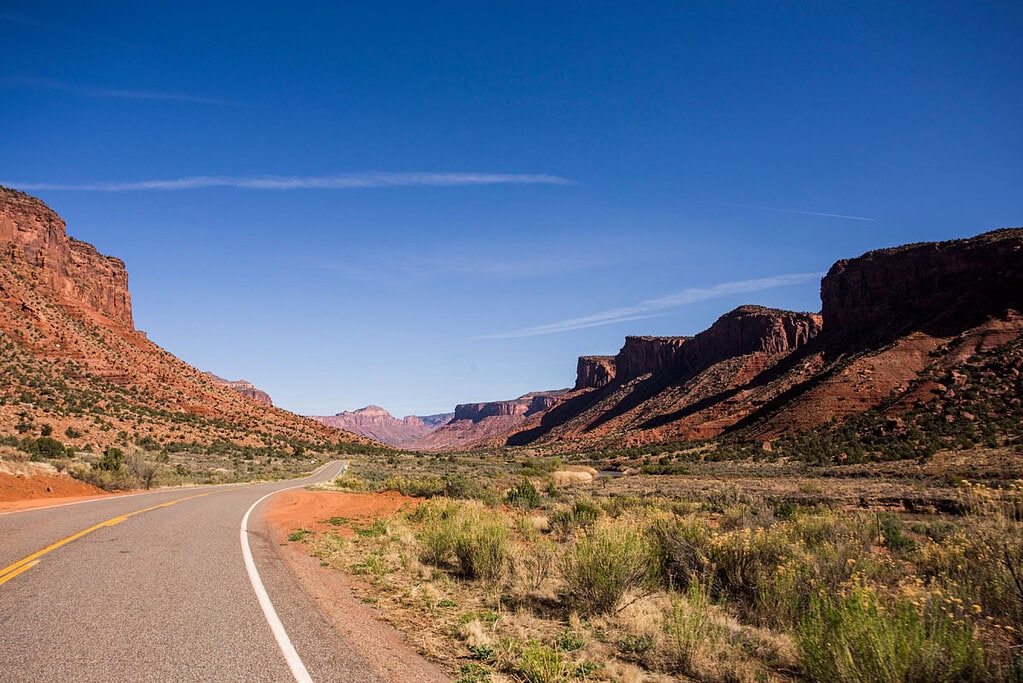 scenic two lane highway weaving through red rock buttes