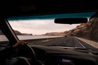 POV driving scenic route alongside lake, cliffs, railroad tracks, ready for boondocking or overlanding.