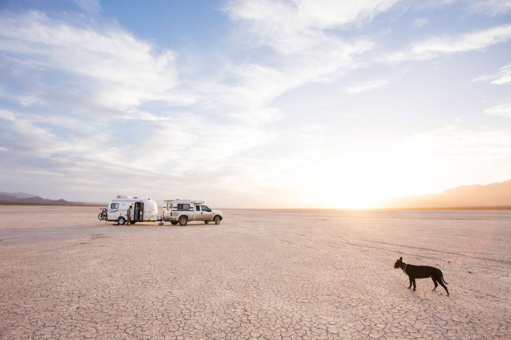 Four Wheel Camper, truck, trailer, dog boondocking off-grid with overlanding setup on dry lakebed.