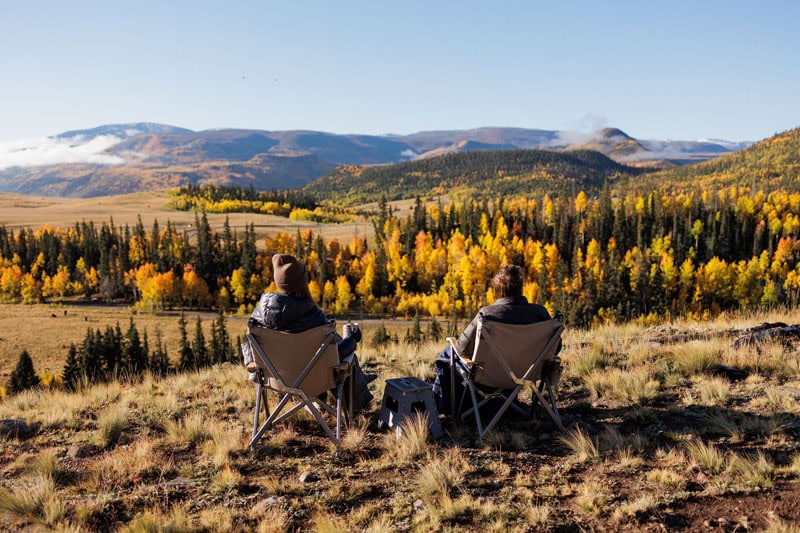 Two people enjoy fall colors, boondocking, off-grid overlanding with Four Wheel Camper.