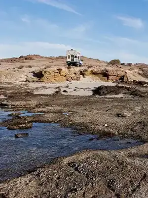 Four Wheel Camper boondocking off-grid by rocky coastline overlanding adventure