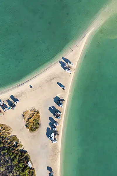 Aerial view of Four Wheel Campers boondocking off-grid for overlanding adventure near clear turquoise waters.