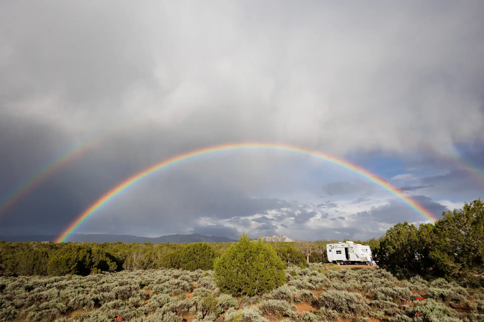 Double rainbow over remote desert landscape with Four Wheel Camper, boondocking off-grid overlanding adventure.