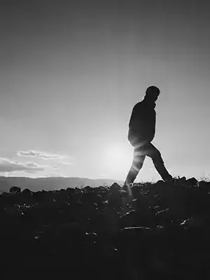 Silhouette person walks rocky terrain during boondocking off-grid overlanding adventure.