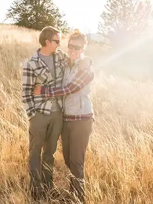Couple embraces amid tall, dry grass, embodying Four Wheel Camper boondocking and off-grid overlanding lifestyle.